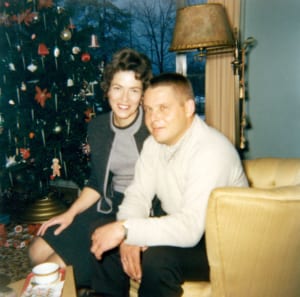 man and woman smiling for photo next to christmas tree