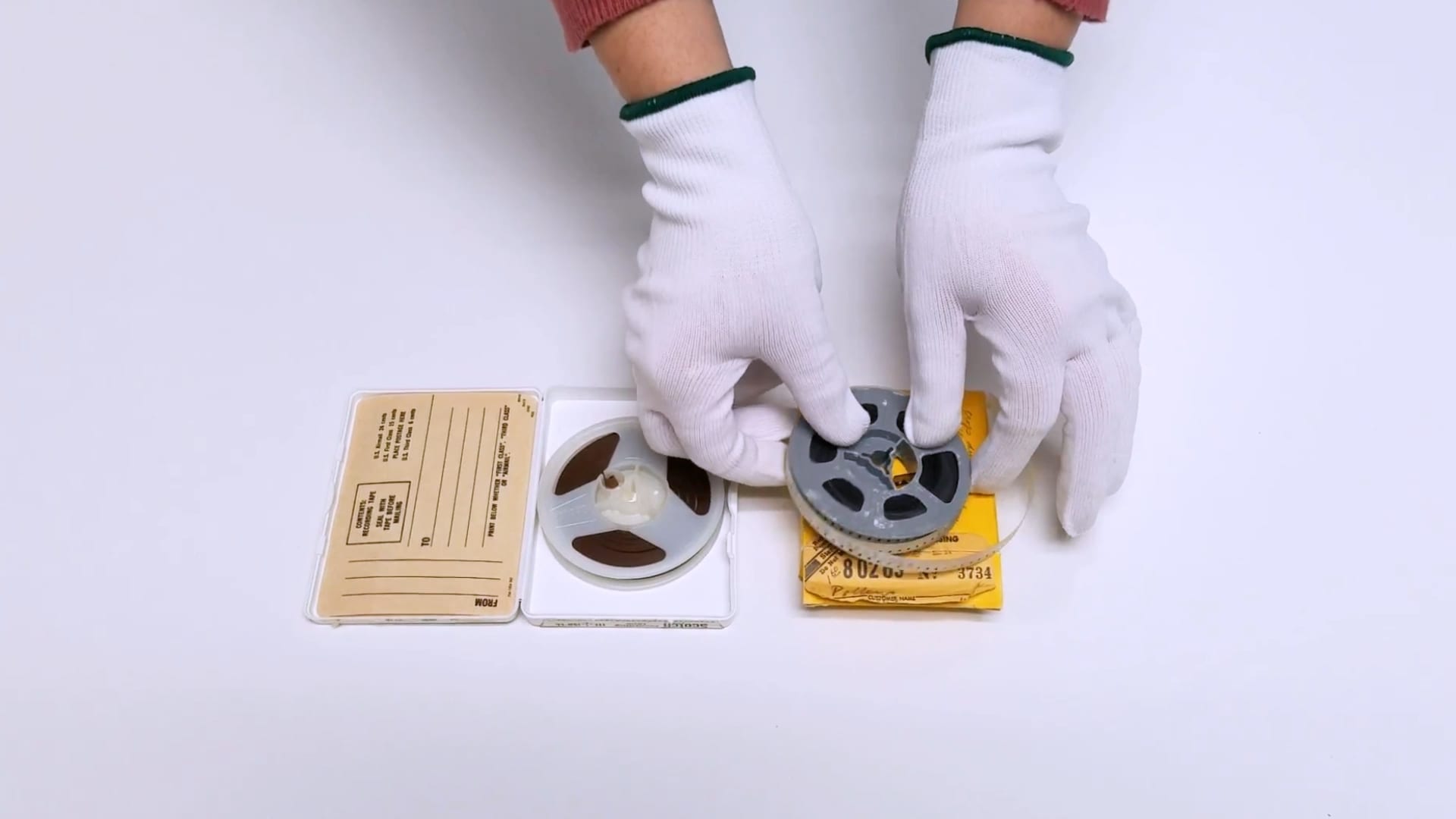 gloved hands with film reel and audio reel side by side