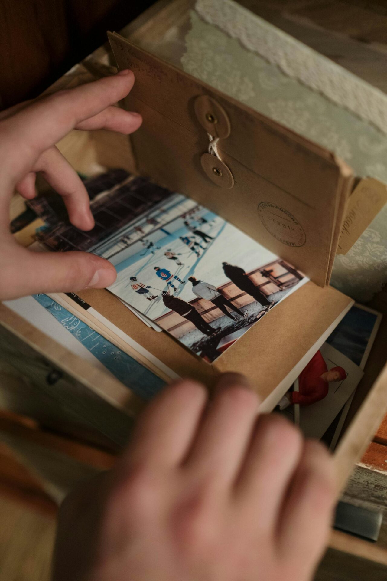 A close-up of hands sorting vintage photos in a drawer, evoking nostalgia.
