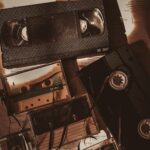 A nostalgic collection of retro VHS and cassette tapes in a sepia-toned flat lay.