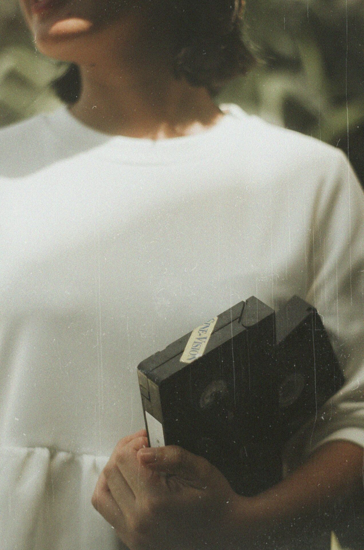 A woman in vintage style holds VHS tapes, evoking nostalgia.