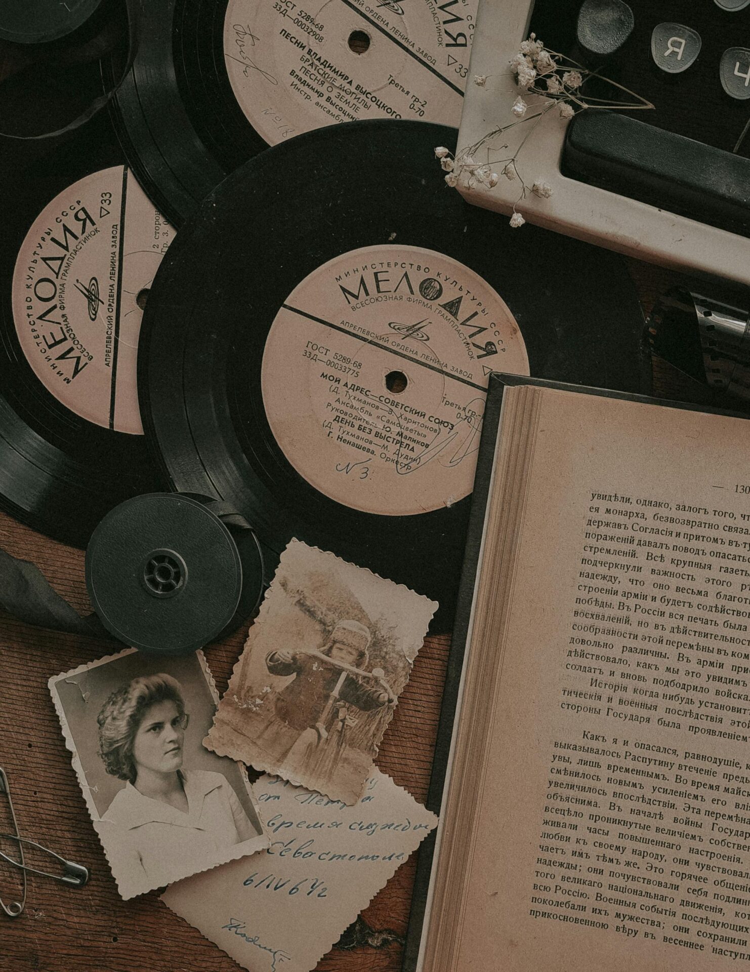 Vintage setup with vinyl records, typewriter, photos, and book for nostalgic aesthetics.