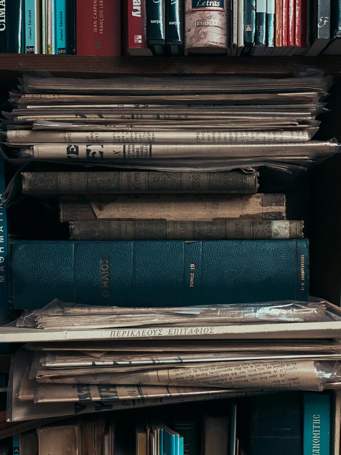 Close-up of a stack of vintage books and newspapers on a shelf. Ideal for literature or vintage themes.