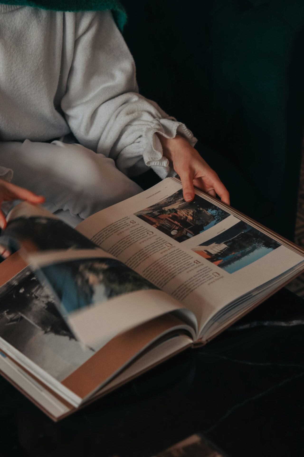 A person relaxing while flipping through a photobook indoors.