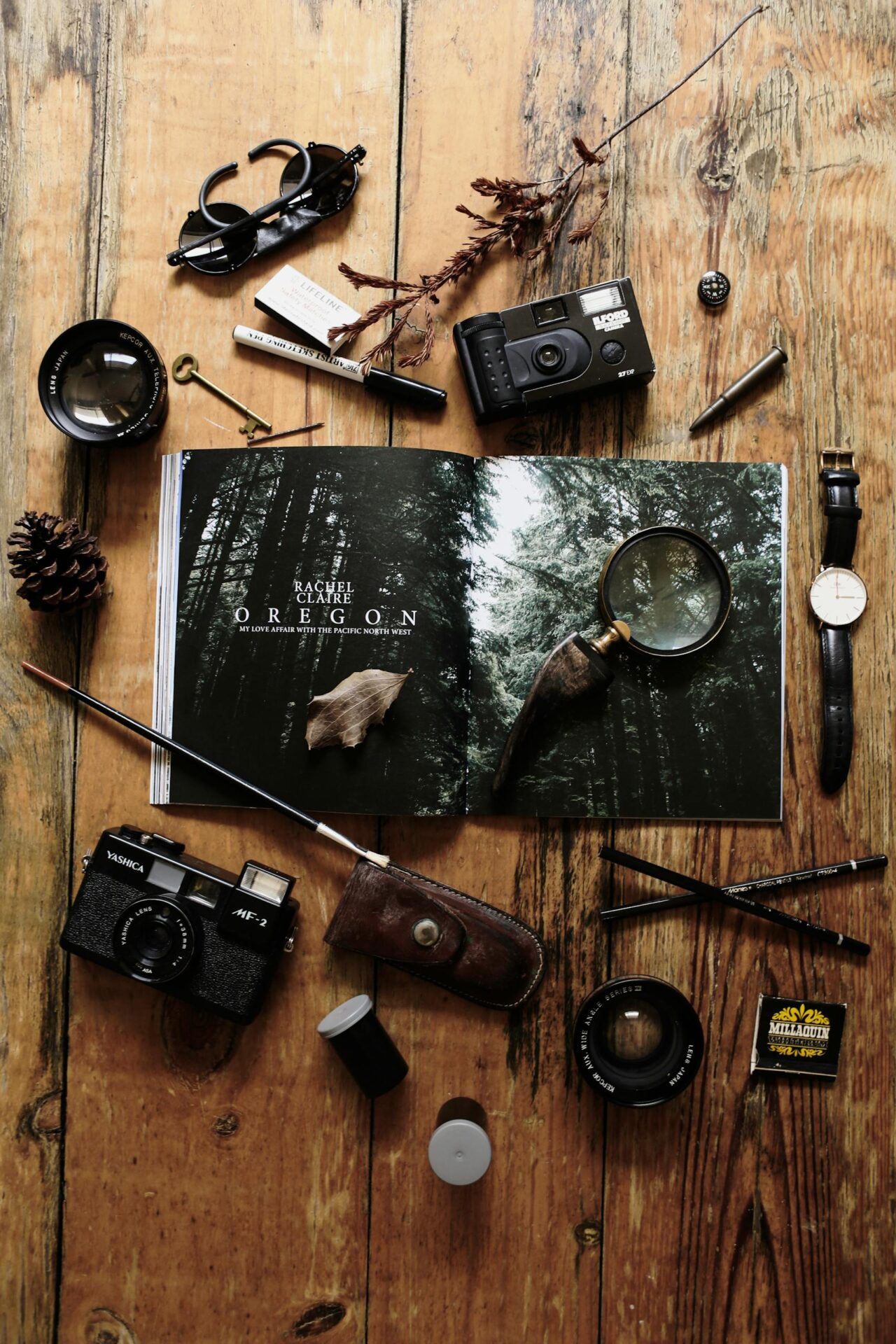 Flat lay of vintage photography gear and an open magazine on a rustic wooden table.